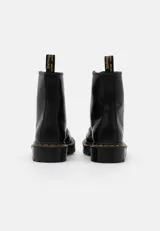 Botas de cuero negro con diseño clásico de 8 ojales, costuras amarillas en la suela y suela de goma acanalada con amortiguación de aire.