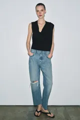 Jeans de tiro medio con corte recto y largo al tobillo. Presentan diseño de cinco bolsillos, cierre frontal con cremallera y botón, y ruedo deshilachado.