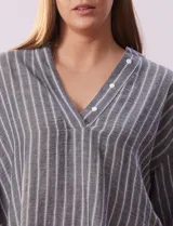 Blusa de poliéster con estampado de rayas verticales, cuello en V con botones, mangas tres cuartos y tajos laterales.