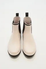 Botas de lluvia bajas color beige con elástico lateral negro y suela de goma negra.