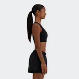 Top deportivo negro de soporte medio, con escote redondo y banda elástica ancha en el bajo. Presenta un bolsillo trasero para teléfono hecho de malla transpirable y copas extraíbles.