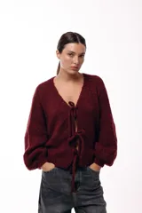 Saco tejido de punto color azul, con escote en V y cierre frontal mediante lazos. Presenta mangas largas amplias con puños ajustados y un calce relajado.