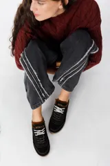 Zuecos de cuero negro con diseño tipo sneaker, cordones y suela de goma color caramelo. Presentan detalle de marca Petra en la lengüeta.