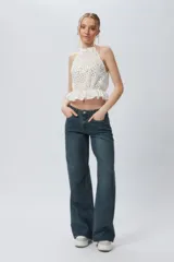 Top blanco sin mangas con cuello halter, bordado con calados y elástico con volado en la cintura.