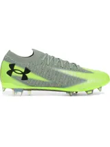 Championes de fútbol Under Armour Shadow Elite 3 FG, diseñados para terreno firme. Presentan una parte superior de tejido IntelliKnit en color gris con detalles en verde neón, logotipo de la marca en negro y suela de fibra de carbono con tapones transparentes.