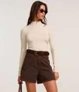 Short de sarga color blanco, corte mom, tiro alto, con trabillas en la cintura y bolsillos. Tiene cierre tradicional por botón y cremallera.