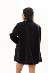 Blazer negro de corte oversize con solapas clásicas, cierre frontal de doble botonadura y bolsillos laterales con solapa.