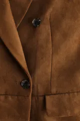 Blazer cruzado marrón con acabado cepillado, solapas de muesca, hombreras y bolsillos delanteros con solapa. Diseño con doble botonadura.