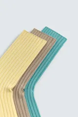 Pack de tres pares de calcetines de algodón con textura acanalada (rib) y efecto lavado. Los colores son amarillo pálido, marrón topo y verde azulado.