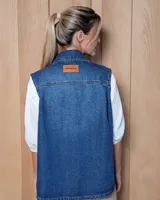 Chaleco de gabardina color tostado, con cuello camisero, cierre frontal con botones metálicos y dos bolsillos frontales con solapa.