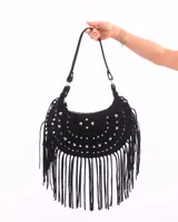 Bolso de hombro estilo boho en color negro, confeccionado en gamuza. Presenta un diseño de media luna decorado con tachas metálicas plateadas y flecos largos en todo el borde inferior. Incluye cierre superior y correa ajustable.