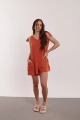 Mono corto color naranja con escote en V, tirantes con lazo y bolsillos laterales.