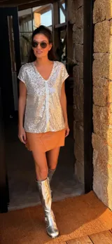 Remera negra de lentejuelas con cuello en V y tira vertical de cuero en el centro. Corte holgado.