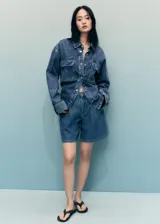 Short de jean de tiro medio con diseño recto, pinzas delanteras, cierre de cremallera y botón, trabillas y bolsillos laterales y traseros.