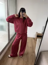 Conjunto de dos piezas color bordó, compuesto por un buzo de cuello redondo con mangas largas y un pantalón de corte holgado con cintura elástica.