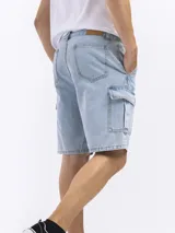 Bermuda de jean azul oscuro, estilo cargo, con bolsillos laterales con tapa a la altura del muslo.