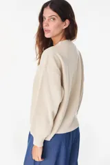 Sweater de punto color amarillo claro, con cuello redondo y diseño holgado. Cuenta con un bordado central en el pecho que representa un sol con su reflejo y la inscripción "PETRA" en tonos naranjas.
