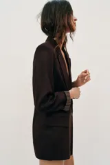 Blazer de lino color verde militar, con cuello solapa, hombreras y manga larga con puño revuelto con detalle a rayas. Cuenta con cierre frontal de un botón y bolsillos delanteros con solapa.
