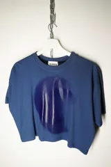 Remera de algodón color azul, de corte holgado y manga corta, con un estampado circular en tono azul más oscuro en el centro del pecho.