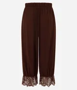 Pantalón bloomer marrón de cintura alta, confeccionado en viscosa con textura crinkle. Cuenta con un diseño amplio y cómodo, perneras voluminosas, puños con elástico interno y aplicación de encaje floral en los puños.