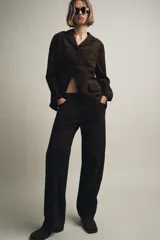 Blazer de mujer color marrón oscuro, confeccionado en piel de ante 100%. Presenta cuello solapa de muescas, manga larga, bolsillos de plastrón frontales y cierre frontal de botones.