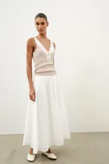 Top de punto canalé en color beige, con escote en pico adornado con una delicada aplicación de encaje blanco y tirantes anchos.