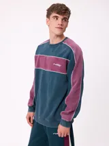 Sweater de cuello redondo marca Rusty, con diseño de bloques de color en azul marino y verde, con detalles de líneas blancas. Presenta el logo de la marca bordado en el pecho.