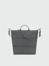 Bolso de viaje Longchamp modelo Le Pliage One, de diseño minimalista y funcional en color azul grisáceo. Cuenta con asas cortas, correa ajustable para el hombro y cierre superior con solapa de botón a presión.