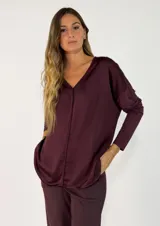 Blusa de satén color bordó, con escote en V, mangas largas y corte holgado.