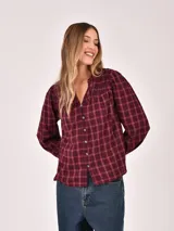 Camisa de manga tres cuartos con cuello mao y cierre frontal de botones. Presenta un diseño a cuadros en tonos oscuros con líneas finas en azul.