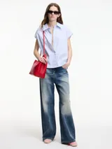 Camisa sin mangas a rayas verticales celestes y blancas, con botones en la parte delantera y trasera, y cuello camisero.