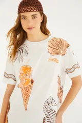 Remera blanca de manga corta y cuello redondo de la marca Farm Rio, con estampado gráfico veraniego que incluye un cono de helado, palmeras y caracoles.