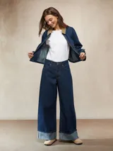 Jean de mezclilla azul oscuro, tiro alto, corte ancho y pierna recta muy amplia, con puños doblados que muestran el interior más claro.