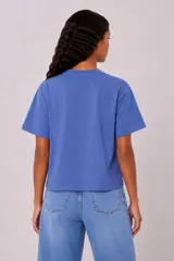 Remera manga corta de algodón color blanco, con cuello redondo y diseño holgado. Cuenta con estampado en el pecho de un paisaje de playa con palmeras en color verde.