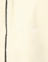 Campera de tejido tipo teddy color crema, con cierre frontal completo, cuello alto y bolsillos laterales con cierre. Presenta detalles de ribetes en color negro en el cuello, puños y cierres.