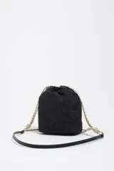 Bolso bucket mini Bimba y Lola de color negro, con cierre de cordón ajustable estilo marinero en tonos beige y negro, bolsillo frontal con solapa y logo estampado de la marca. Cuenta con asa larga ajustable.