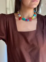 Collar corto con cuentas de cerámica, cristales checos y acrílico de diferentes colores y formas. Incluye una concha roja como dije central.