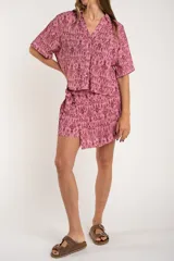Camisa de manga corta con estampado abstracto en tonos rosa y borgoña. Tiene cuello camisero, cierre frontal con botones y corte oversize.