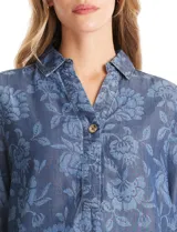 Blusa de lyocell con estampado floral en tonos azules, cuello con solapa, escote en V con botón frontal, mangas tres cuartos con puño ancho y ruedo curvo.