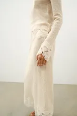 Falda midi de tejido rústico en color beige, con tiro medio, cintura elástica y detalle de aplicación de crochet en el bajo.