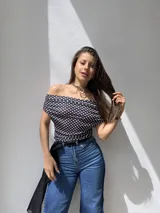 Top de escote bote y hombros descubiertos, confeccionado en tela elastizada con estampado de lunares blancos sobre fondo negro.