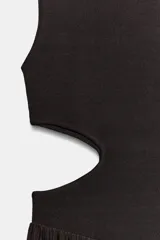Vestido midi de color negro, sin mangas, con cuello redondo y aberturas laterales en la cintura (cut out). La parte superior es de punto liso y la falda presenta una textura plisada y ligera.