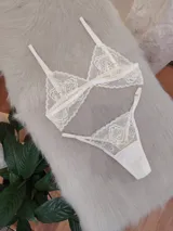 Conjunto de lencería compuesto por un bralette triangular y una bombacha tipo tanga, ambos confeccionados en encaje floral color champagne con terminaciones delicadas.