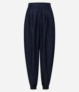 Pantalón de jean estilo aladín con cintura alta y pretina estructurada. Presenta pinzas frontales, volumen en la cadera y piernas con entalle progresivo que finalizan en puños con elástico, logrando un efecto jogger sofisticado.