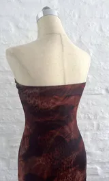 Vestido corto marrón con estampado animal print, corte ajustado, escote strapless con aberturas en el frente y breteles finos.