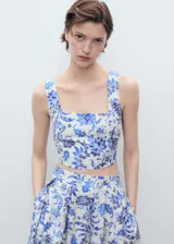 Top corto de tela color crema con estampado floral azul, de breteles anchos y escote cuadrado.