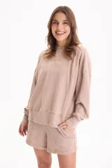 Buzo deportivo sin frisa de color beige con efecto lavado, cuello redondo, mangas largas y estampa frontal con texto bordado.