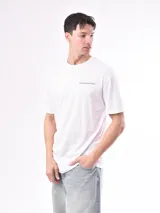 Remera blanca de algodón con cuello redondo y estampado pequeño en el pecho con la frase "Enjoy the simple pleasures".