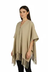 Poncho abierto de color beige con flecos en el borde inferior y escote en V.