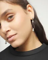 Pendientes largos con base de bola plateada, tira de cuero marrón en forma de gota y detalle de bola plateada en el extremo.